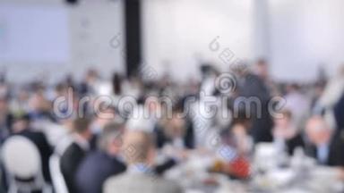背景模糊的餐饮服务服务员在婚礼或会议上把盘子和盘子放在客人的桌子上。